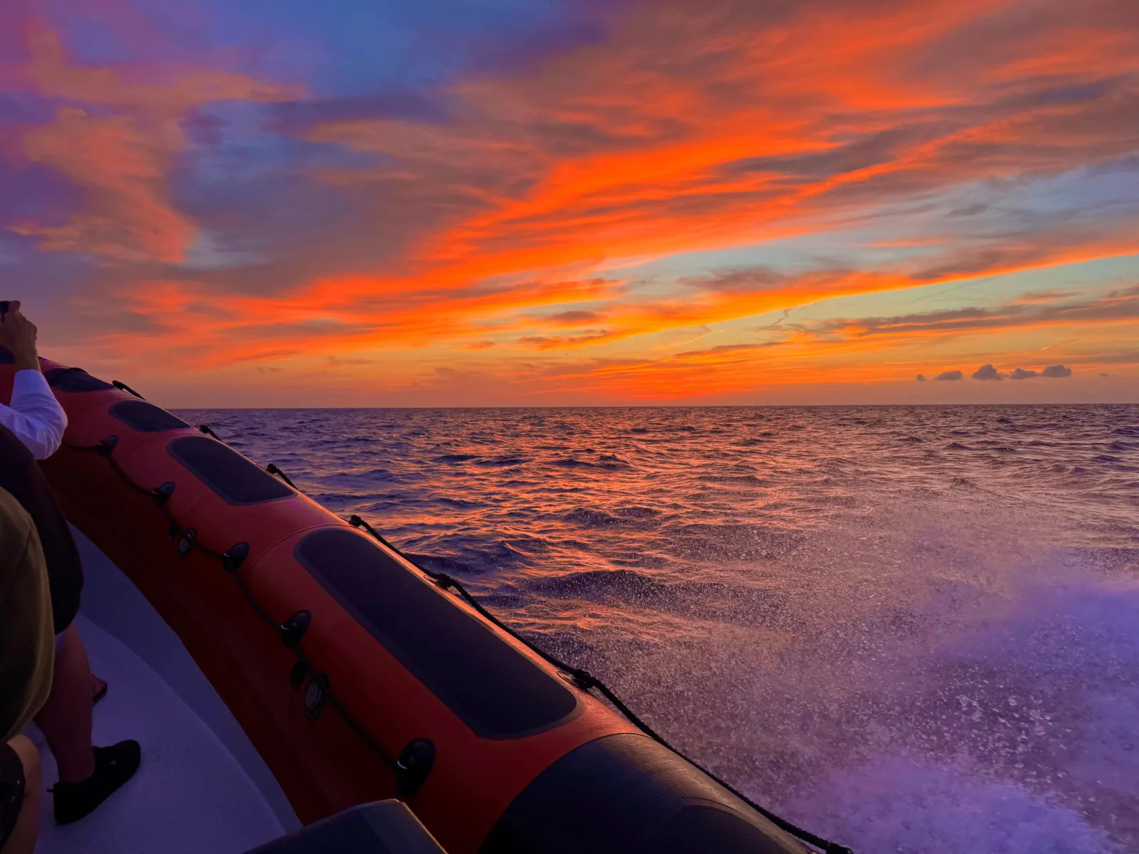 The speedboat's bow against a red and orange dawn sky