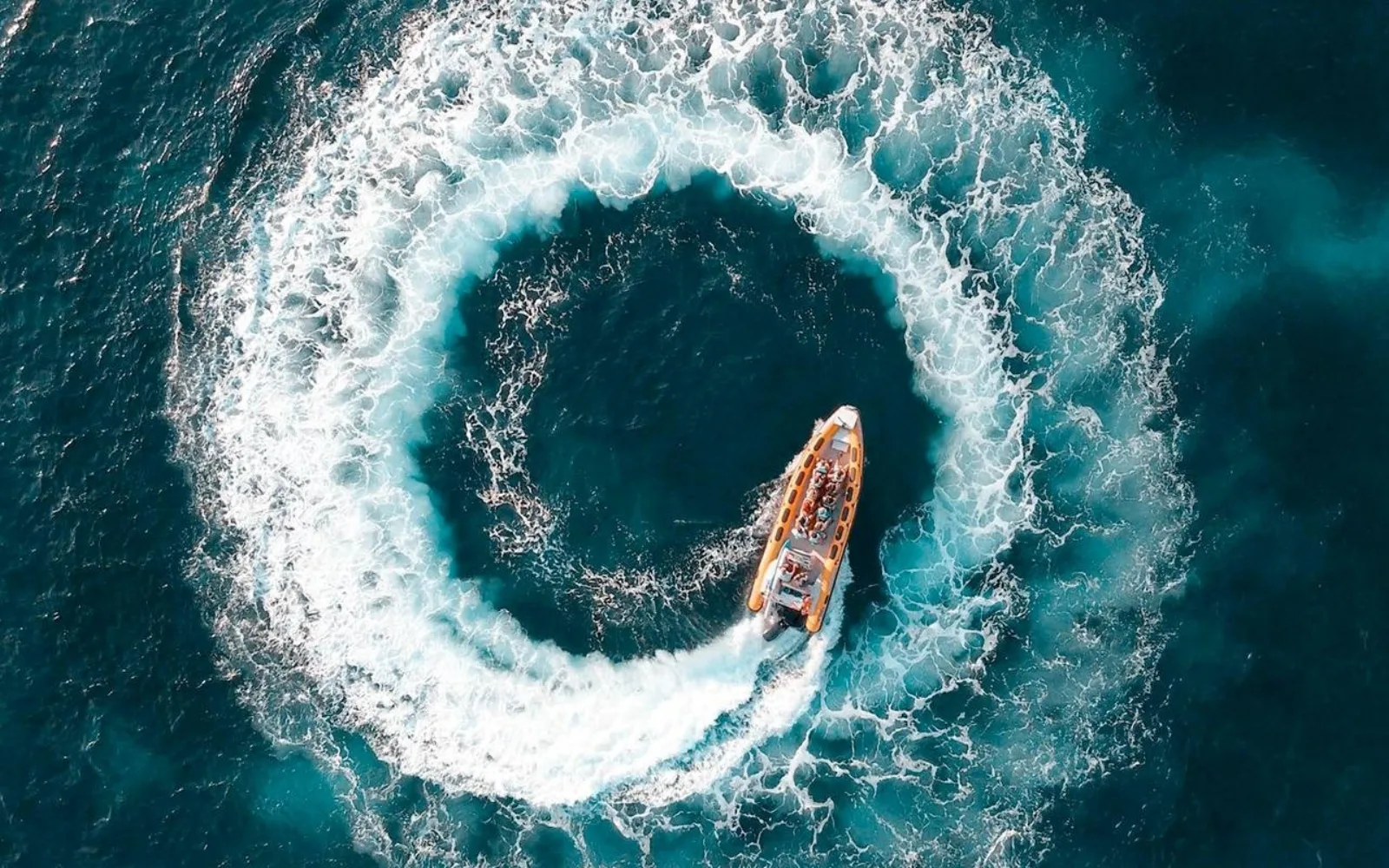 The speedboat cutting a full circle in open water, seen from above