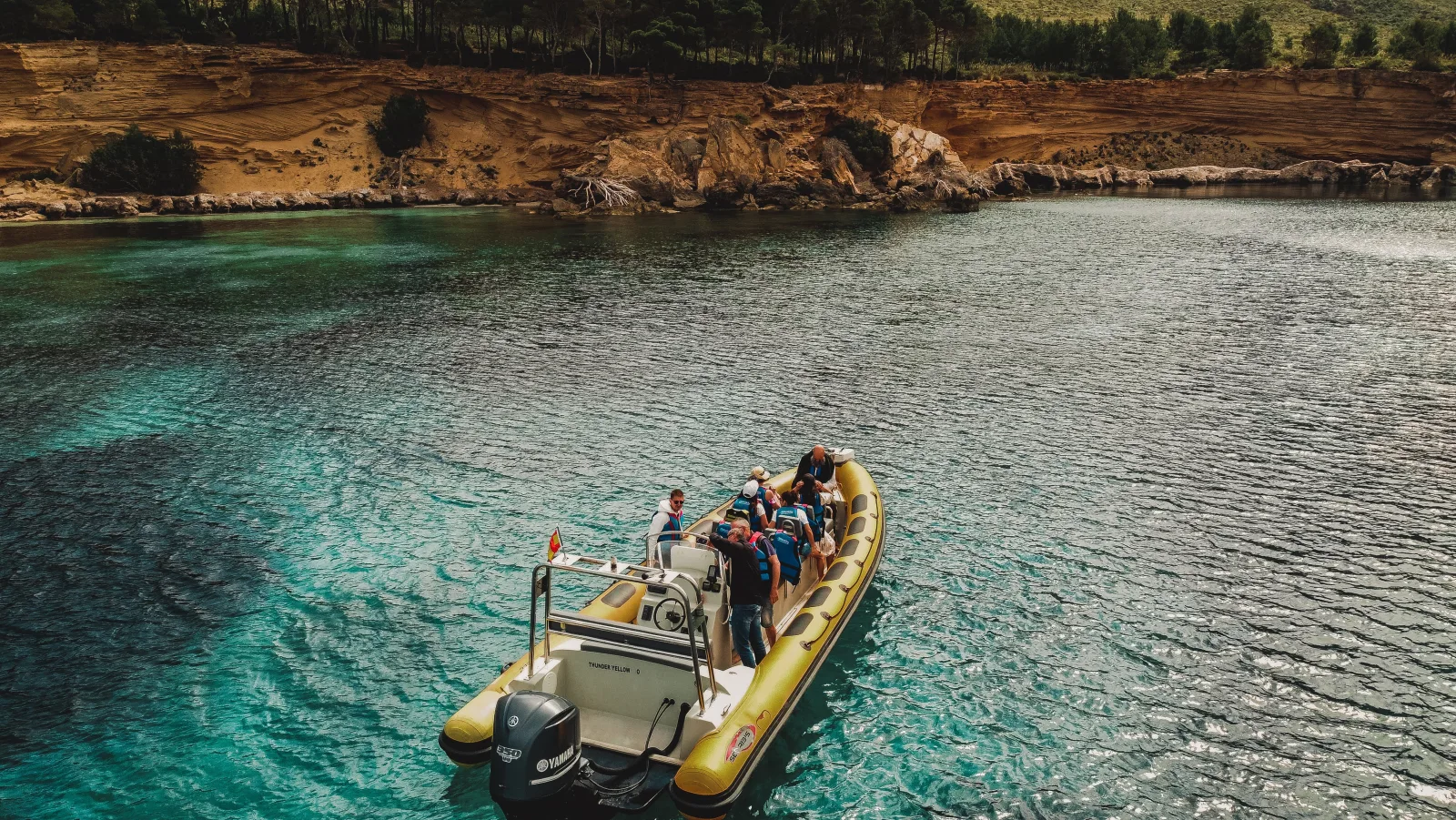 The speedboat anchored off an undeveloped, rocky stretch of shoreline