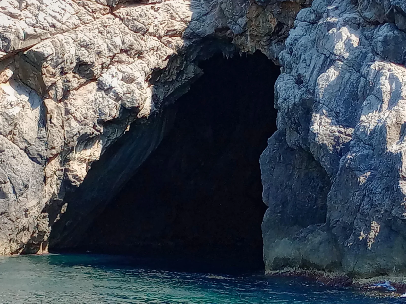 The dark mouth of a sea cave in the limestone cliffs of Mallorca's north coast