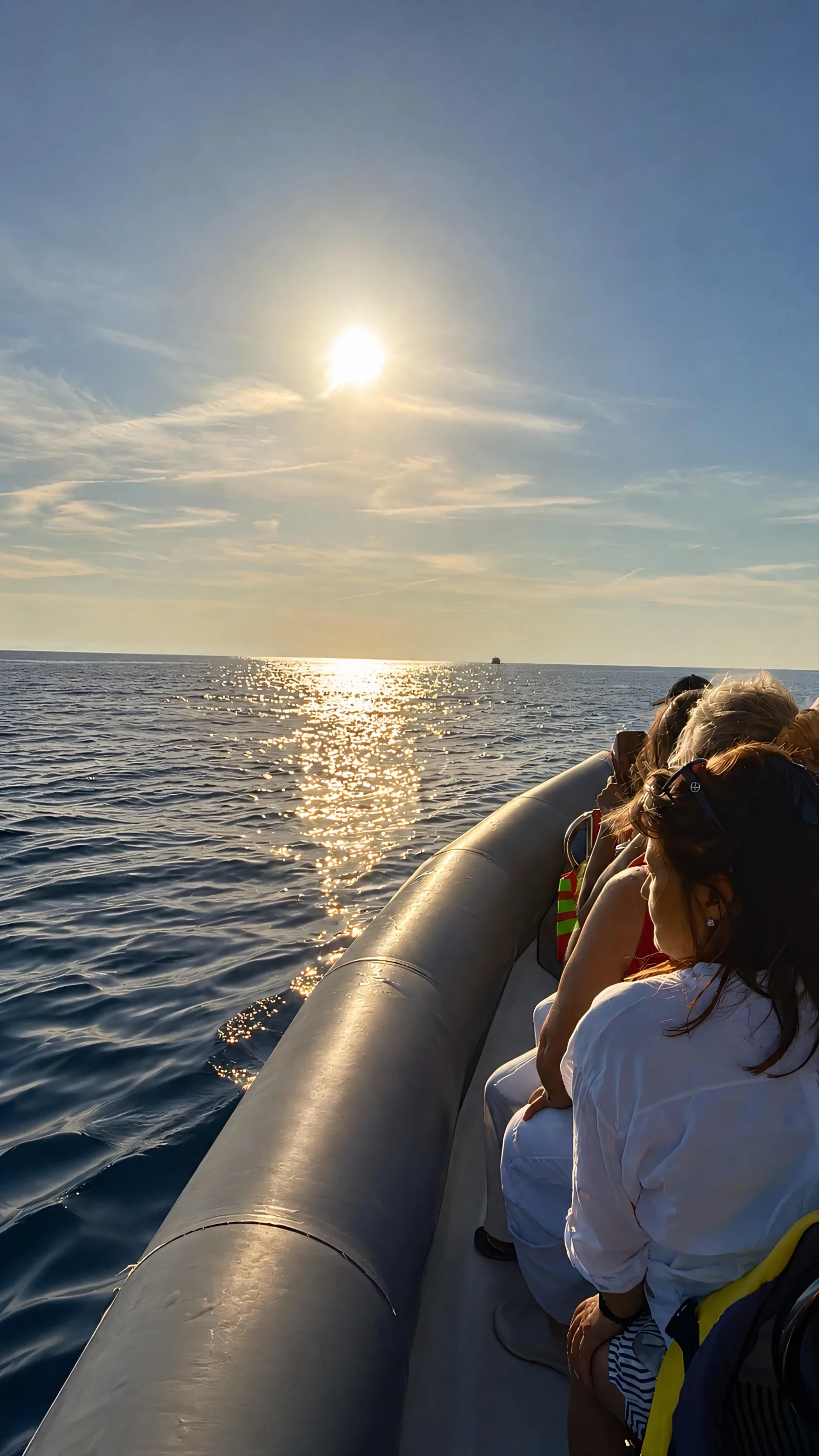 The small group on the boat's tubes as the sun comes up over the sea